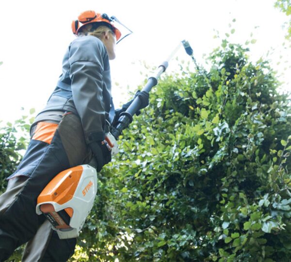miljöbild av en man som klipper häck med stånghäcksax från Stihl