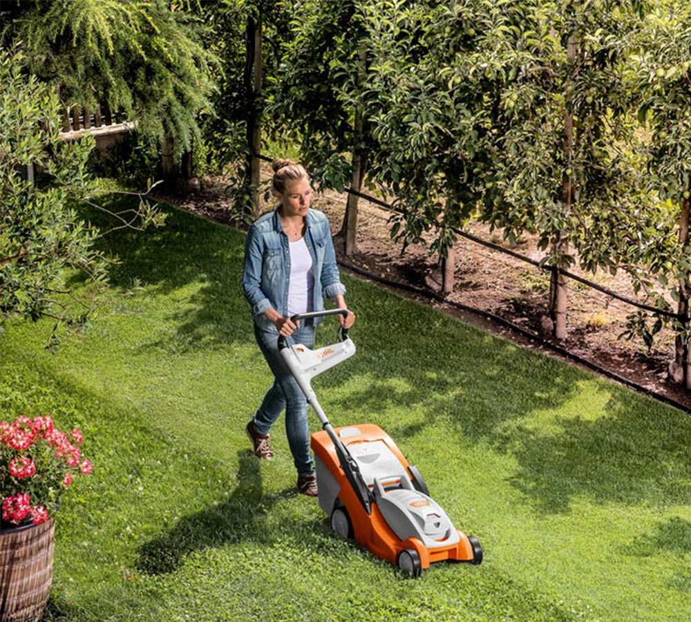 Ung kvinna klipper gräset med batteriklippare från Stihl